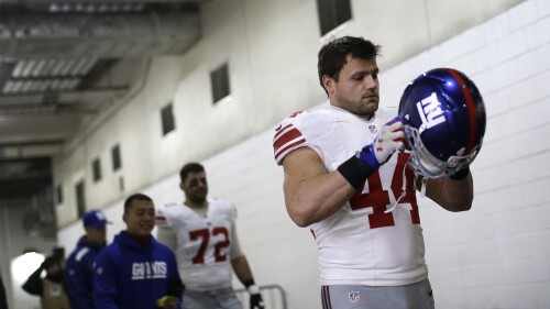 FILE - New York Giants running back Peyton Hillis puts his helmet on as he walks through a tunnel to the field before an NFL football game against the Washington Redskins, Dec. 1, 2013, in Landover, Md. When the former running back's mother pointed to his son and niece off a Florida beach and said they were drowning, he said he didn’t think and just ran for the water. Hillis saved the children from a rip current off the coast of Pensacola in January 2023, but he said in an interview broadcast Tuesday, June 13, that the scariest moment was swimming past his 9-year-old son, Orry, to his 8-year-old niece, who was in more danger. (AP Photo/Patrick Semansky, File)