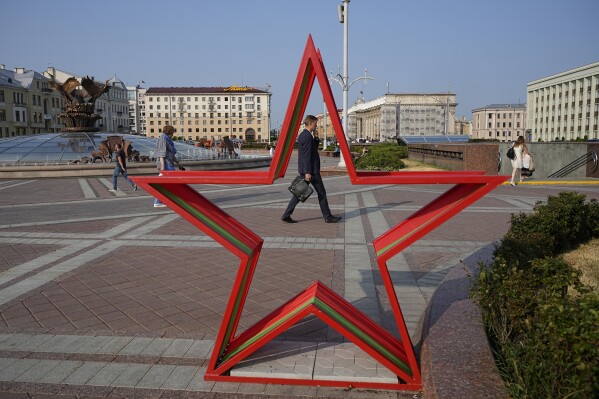 People walk in Independent Square during sunset in Minsk, Belarus, Wednesday, July 5, 2023. (AP Photo/Alexander Zemlianichenko)
