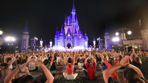 On the morning of the summer solstice, Walt Disney World cast members stretch at Cinderella Castle in the Magic Kingdom, in Lake Buena Vista, Fla., in a pre-dawn gathering before the park opened Wednesday, June 21, 2023, for their annual team yoga session to commemorate International Yoga Day. An estimated 2,000 employees participated in Wednesday's rain-shortened event, now in its 7th year at Disney World. The International Day of Yoga occurs worldwide each year on the summer solstice and was established by the U.N. General Assembly in 2014. (Joe Burbank/Orlando Sentinel via AP)