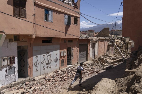 A man runs as he arrives to recover items from his home which was damaged by the earthquake, in the town of Amizmiz, near Marrakech, Morocco, Sunday, Sept. 10, 2023. (AP Photo/Mosa'ab Elshamy)