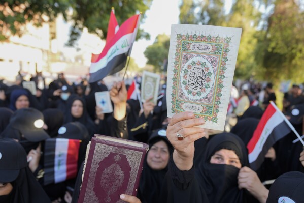 Iraqis raise copies of the Quran, Muslims' holy book, during a protest in Baghdad, Iraq, Saturday, July 22, 2023. Hundreds of protesters have attempted to storm Baghdad’s heavily fortified Green Zone, which houses foreign embassies and the seat of Iraq’s government, following reports of the burning of a Quran by a ultranationalist group in front of the Iraqi Embassy in Copenhagen. (AP Photo/Hadi Mizban)