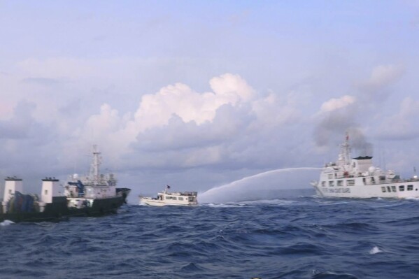 In this handout photo provided by the Philippine Coast Guard, a Chinese Coast Guard ship uses water cannons on Philippine navy-operated supply boat M/L Kalayaan as it approaches Second Thomas Shoal, locally known as Ayungin Shoal, in the disputed South China Sea on Sunday Dec. 10, 2023. The Chinese coast guard targeted Philippine vessels with water cannon blasts Sunday and rammed one of them, causing damage and endangering Filipino crew members off a disputed shoal in the South China Sea, just a day after similar hostilities at another contested shoal, Philippine officials said.(Philippine Coast Guard via AP)