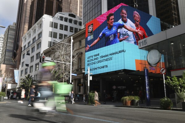 A FIFA Women's World Cup billboard is seen in the central business district ahead of the opening match in Auckland, New Zealand, Wednesday, July 19, 2023. International visitors are greeted at the arrivals hall in Auckland's airport with a display of Women's World Cup branding, including carpeting like a soccer pitch. After that, though, the hype trails off. (AP Photo/Rafaela Pontes)