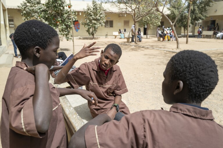Mouhamed Sall, who is deaf, communicates by sign with his classmates at the Guinaw Rail Sud public high school in Pikine, Senegal, Monday, March 18, 2024. Sall and three other students are part of a new approach in a small number of schools in Senegal that seat those who are deaf and hard of hearing with the rest of the class. (AP Photo/Sylvain Cherkaoui)