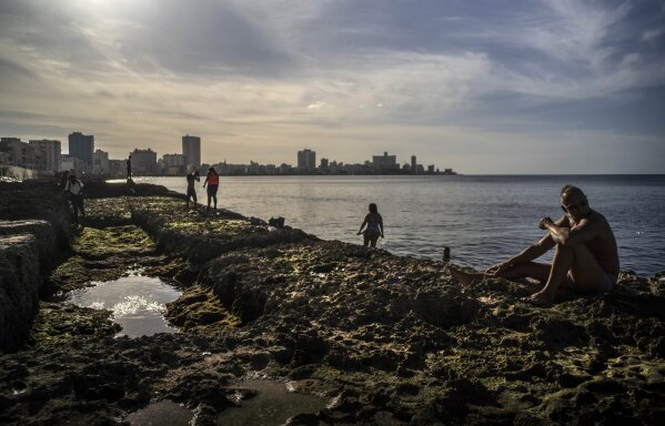 People take a sunbath at sunset on the Malecon in Havana, Cuba, Friday, Jan 1, 2021. (AP Photo/Ramon Espinosa)