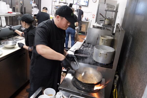FILE - Tito Thepkaysone cooks up some pad Thai at "Love & Thai" restaurant in Fresno, Calif., Wednesday, Dec. 20, 2023. The Thai restaurant was wrongfully accused of abusing a dog to turn it into meat, a false claim rooted in a racist stereotype. (AP Photo/Richard Vogel, File)