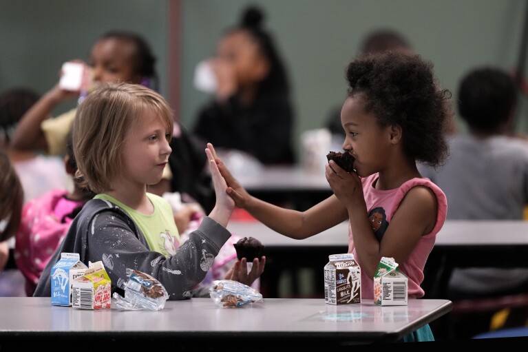 Third grader Katherine Nelson, left, and Shawn Kennedy, kindergarten, talk during breakfast at Williams Science and Arts Magnet school Friday, May 10, 2024, in Topeka, Kan. (AP Photo/Charlie Riedel)