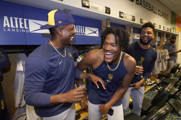 Milwaukee Brewers players Thyago Vieira, left, and Abner Uribe, center, and Joel Payamps, right, celebrate in the clubhouse after the Brewers beat the Miami Marlins 16-1 in a baseball game and clinching a postseason berth, Friday, Sept. 22, 2023, in Miami. (AP Photo/Wilfredo Lee)
