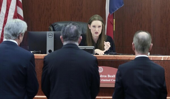 Defense and special prosecutors approach the bench of Judge Andrea Beall for suspended Texas Attorney General Ken Paxton's fraud case at Harris County Courthouse on Thursday, Aug. 3, 2023 in Houston. Embattled Texas Attorney General Ken Paxton's years-delayed trial on securities fraud charges will have to wait until his separate impeachment trial is concluded, lawyers and the judge in the case said Thursday. (Elizabeth Conley/Houston Chronicle via AP)