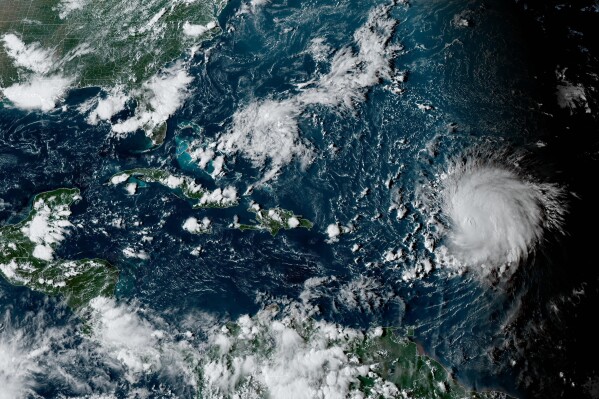This satellite image provided by the National Oceanographic and Atmospheric Administration shows Hurricane Lee, right, in the Atlantic Ocean on Friday, Sept. 8, 2023, at 4:50 p.m. EDT. Lee is rewriting old rules of meteorology, leaving experts astonished at how rapidly it grew into a goliath Category 5 hurricane. (NOAA via AP)