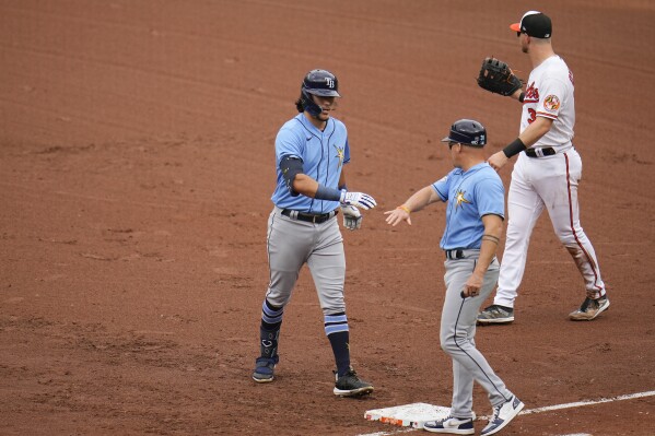 Tampa Bay Rays' Tristan Gray, left, reacts with first base coach Chris Prieto after collecting his first major league hit in the fifth inning of a baseball game against the Baltimore Orioles, Sunday, Sept. 17, 2023, in Baltimore. (AP Photo/Julio Cortez)