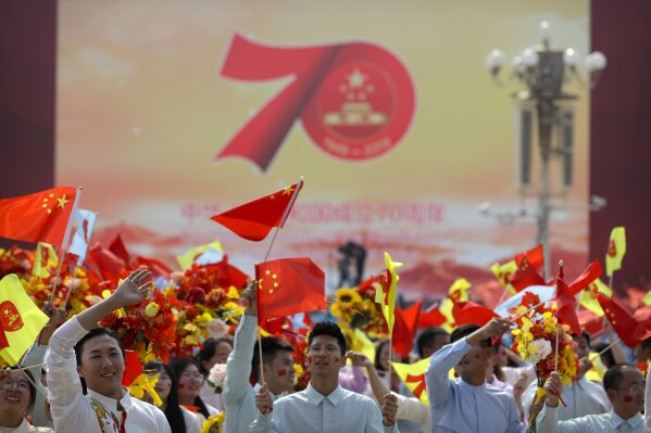 Participants wave flags during a parade to commemorate the 70th anniversary of the founding of Communist China in Beijing, Tuesday, Oct. 1, 2019. Trucks carrying weapons including a nuclear-armed missile designed to evade U.S. defenses rumbled through Beijing as the Communist Party celebrated its 70th anniversary in power with a parade Tuesday that showcased China's ambition as a rising global force. (AP Photo/Mark Schiefelbein)