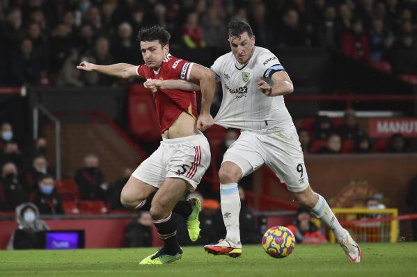Manchester United's Harry Maguire, left, challenges for the ball with Burnley's Chris Wood during the English Premier League soccer match between Manchester United and Burnley at Old Trafford in Manchester, England, Thursday, Dec. 30, 2021. (AP Photo/Rui Vieira)
