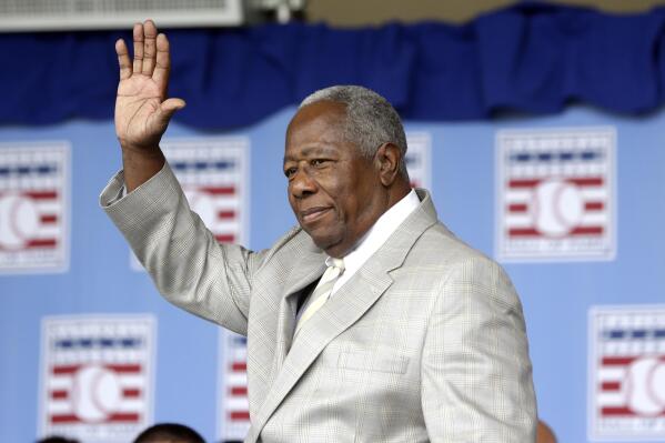 FILE - Hall of Famer Hank Aaron waves to the crowd during the Baseball Hall of Fame induction ceremony on Sunday, July 28, 2013, in Cooperstown, N.Y. Aaron made history with one swing of his bat. A year later and on the other side of Georgia, Lee Elder made history with one swing of his driver. Their deaths in 2021 were mourned beyond the sports world and were reminders of the hate, hardships and obstacles they endured with dignity on their way to breaking records and barriers. (AP Photo/Mike Groll, File)