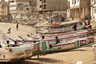 FILE - Children play on fishing boats known as "pirogues" in Dakar, Senegal, on June 24, 2023. More than 60 migrants are feared dead after coast guards off the Atlantic island of Cape Verde rescued a boat that started with more than 100 aboard, authorities and migrant advocates said. The Spanish migration advocacy group Walking Borders said the vessel was a large fishing boat, called a pirogue, which had left Senegal on July 10. (AP Photo/Zane Irwin, File)