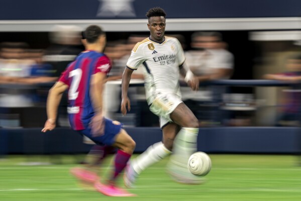 Real Madrid forward Vinicius Jose Paixao, right, tries to dribble past FC Barcelona defender Sergino Dest (2) during the second half of a Champions Tour soccer match, Saturday, July 29, 2023 at AT&T Stadium in Arlington, Texas. FC Barcelona won 3-0. (AP Photo/Jeffrey McWhorter)