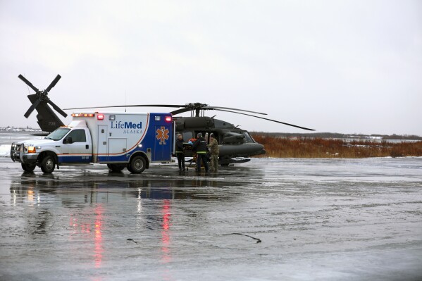 CORRECTS TO BALINDA O'NEAL - This photo provided by the Alaska National Guard shows,from the left, Holly Demmert and Clifton Dalton, both flight paramedics with LifeMed, and Chief Warrant Officer 3 Bryan Kruse, Bethel Army Aviation Operating Facility commander, move a critically ill patient from an AKARNG UH-60L Black Hawk helicopter to an ambulance during a medical evacuation from Napaskiak to Bethel, Wednesday, Nov. 15, 2023 in Bethel, Alaska. (Balinda O'Neal/Alaska National Guard via AP)