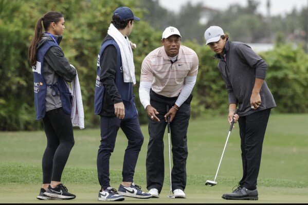 Tiger Woods, second from right, and son Charlie, right, talk about putt while caddies, daughter Sam, left, and Luke Wise, second from left, look on during the final round of the PNC Championship golf tournament Saturday, Dec. 16, 2023, in Orlando, Fla. (AP Photo/Kevin Kolczynski)