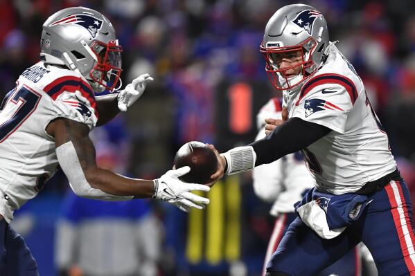 New England Patriots quarterback Mac Jones, left, hands off to cornerback J.C. Jackson during the first half of an NFL football game against the Buffalo Bills in Orchard Park, N.Y., Monday, Dec. 6, 2021. (AP Photo/Adrian Kraus)