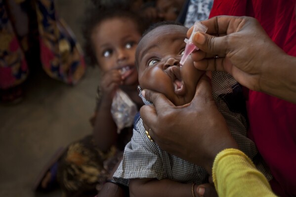 FILE-- In this file photo, a Somali baby receives a polio vaccine, at the Medina Maternal Child Health center in Mogadishu, Somalia. Zimbabwe has started an emergency campaign to inoculate more than 4 million children against polio after health authorities detected 3 cases caused by a rare mutation of the weakened virus used in oral vaccines, including a 10-year-old girl who was paralyzed in January. (AP Photo/Ben Curtis, File)