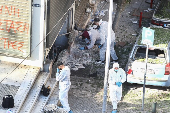 Greek police forensic experts search the spot where a 38-year-old woman was killed early Saturday when a bomb she was carrying exploded in her hands, local police said, in Thessaloniki, northern Greece, May 3, 2025. (AP Photo/Giannis Papanikos)