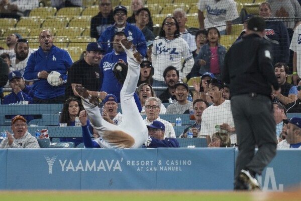 Los Angeles Dodgers first baseman Freddie Freeman (5) falls in to the net on top of fans as he catches a foul ball hit by Detroit Tigers' Matt Vierling during the sixth inning of a baseball game in Los Angeles, Tuesday, Sept. 19, 2023. (AP Photo/Ashley Landis)