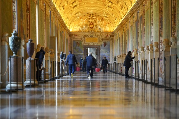 FILE - Museums employees walk down an aisle of the Vatican Museums as they prepare to open the museum, at the Vatican, Monday, Feb. 1, 2021. Forty-nine employees of the Vatican Museums have filed a class-action complaint with the Vatican administration demanding better seniority, leave and overtime benefits in an unusual, public challenge to Pope Francis’ governance. The complaint, dated April 23, 2024, was made public the weekend of May 10, 2024, in Italian newspapers. (Ǻ Photo/Andrew Medichini, File)