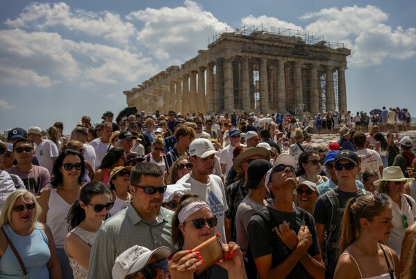 FILE - Tourists visit the Parthenon temple atop the Acropolis ancient hill in Athens, Greece, Tuesday July 4, 2023. From April 1, 2024 Greece is planning to offer exclusive, guided tours of the Acropolis, its most powerful tourist magnet, to handfuls of well-heeled visitors outside normal opening hours. It will cost 5,000 euros ($5,500) for a group of up to five people. (AP Photo/Thanassis Stavrakis, File)