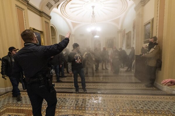 FILE - In this Jan. 6, 2021, file photo, smoke fills the walkway outside the Senate Chamber as violent rioters loyal to President Donald Trump are confronted by U.S. Capitol Police officers inside the Capitol in Washington. New details from the deadly riot of Jan. 6 are contained in a previously undisclosed document prepared by the Pentagon for internal use that was obtained by the Associated Press and vetted by current and former government officials. (AP Photo/Manuel Balce Ceneta, File)