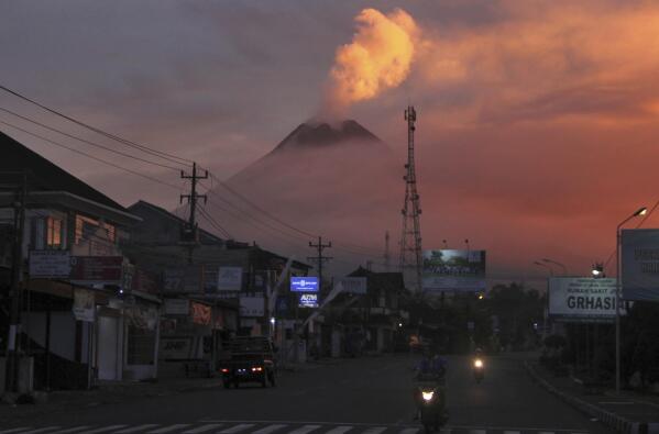 Motorists ride past as Mount Merapi looms in the background, in Sleman, Friday, June 25, 2021. Indonesia’s most volatile volcano erupted Friday, releasing plumes of ash high into the air and sending streams of lava with searing gas clouds flowing down its slopes. (AP Photo/Slamet Riyadi)