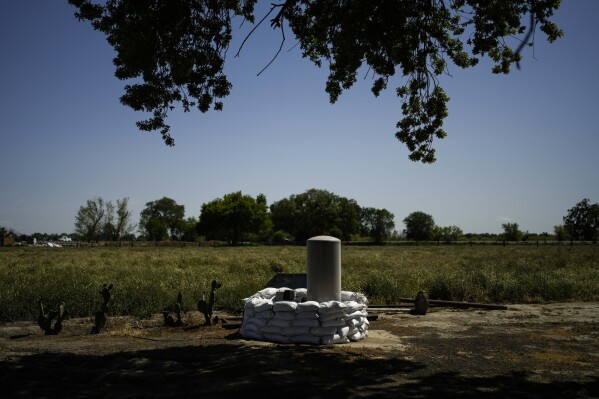 FILE - Sandbags are stacked around a well in anticipation of flooding of the Kings River in the Island District of Lemoore, Calif., April 19, 2023. California officials are considering whether to take over monitoring groundwater use in the fertile San Joaquin Valley under a landmark law aimed at protecting water flow to homes and farms. The Tuesday, April 16, 2024, hearing before the State Water Resources Control Board is the first of its kind since California passed a groundwater management law a decade ago. (AP Photo/Jae C. Hong, File)