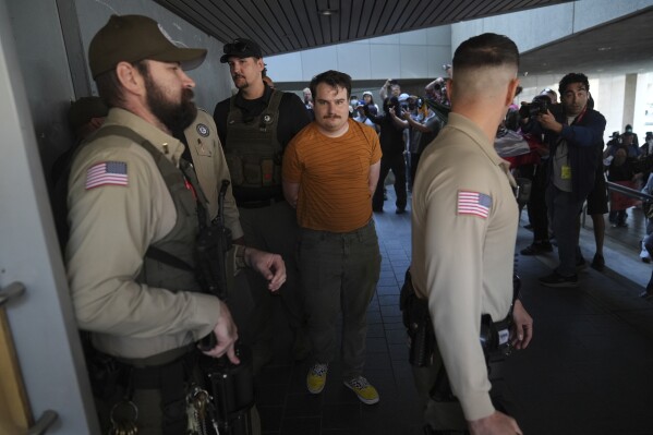 Law enforcement detain a protester at the U.S. Department of Justice Federal Bureau of Prisons after federal immigration authorities conducted an operation on Friday, June 6, 2025, in Los Angeles. (AP Photo/Jae C. Hong)