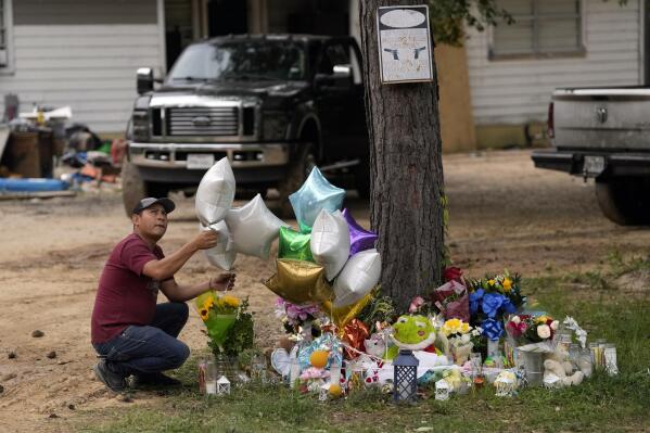 A man releases a balloon from the makeshift memorial outside the victims' home Tuesday, May 2, 2023, where a mass shooting occurred Friday, in Cleveland, Texas. The search for the suspected gunman who allegedly shot five of his neighbors, including a child, after they asked him to stop firing off rounds in his yard stretched into a fourth day Tuesday. (AP Photo/David J. Phillip)