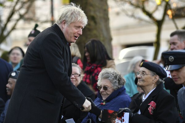 Britain's Prime Minister Boris Johnson, left, greets a veteran, as he attends a remembrance service on Armistice Day, the 101st anniversary of the end of the First World War, in Wolverhampton, England, Monday,  Nov. 11, 2019, while on the General Election campaign trail. (Ben Stansall/Pool Photo via AP)