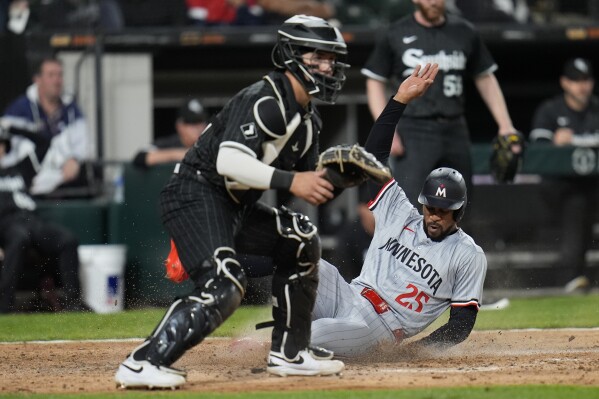 Minnesota Twins center fielder Byron Buxton, right, slides into home past Chicago White Sox catcher Korey Lee, left, to score on a single by Max Kepler during the ninth inning of a baseball game Monday, April 29, 2024, in Chicago. (AP Photo/Erin Hooley)