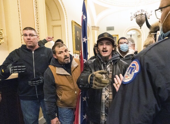 Violent protesters loyal to President Donald Trump, including Kevin Seefried, center, holding a Confederate battle flag, are confronted by U.S. Capitol Police officers outside the Senate Chamber inside the Capitol, Jan. 6, 2021 in Washington. (AP Photo/Manuel Balce Ceneta, File)
