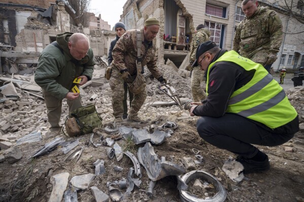 Ukrainian military experts gather remains of a missile next to a destroyed building in the Pecherskyi district, after a Russian air attack in Kyiv, Ukraine, Monday March 25, 2024. Five people were injured in the strike, two were hospitalized. (AP Photo/Vadim Ghirda)