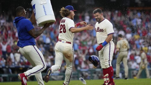 Philadelphia Phillies' Kyle Schwarber, right, celebrates with Alec Bohm, center, and Gregory Soto after hitting a game-winning RBI-sacrifice fly against San Diego Padres relief pitcher Tim Hill during the 12th inning of a baseball game, Sunday, July 16, 2023, in Philadelphia. (AP Photo/Matt Slocum)