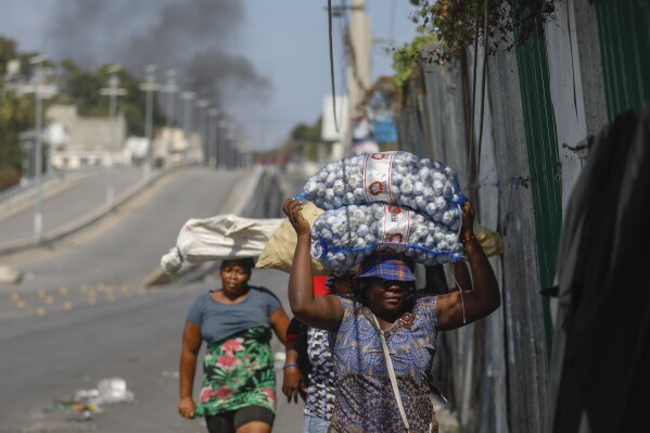 DOSSIER – Des vendeurs ambulants courent lors d’affrontements entre la police et des gangs à Port-au-Prince, en Haïti, le mercredi 6 mars 2024. (AP Photo/Odelyn Joseph, File)