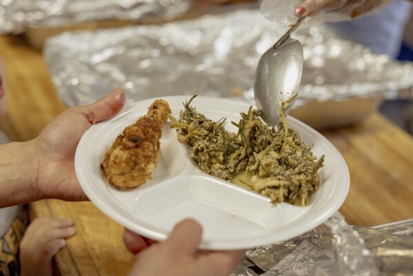 A person is served at the Springfield United Methodist Church in Okemah, Okla., at the annual wild onion dinner on April 6, 2024. Wild onions are among the first foods to grow in the spring, and the dinners have been a tradition in Native American communities for generations. (AP Photo/Brittany Bendabout)