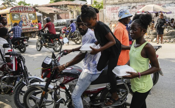 Juliana St. Vil returns with a container of food to the shelter where she now lives with her family after fleeing gang violence in their neighborhood, in Port-au-Prince, Haiti, Wednesday, May 15, 2024. The 12-year-old and nearly a dozen other children receive a free meal every day before the taking part in acting workshops. Like others, she only eats half and saves the rest for her family. (AP Photo/Ramon Espinosa)