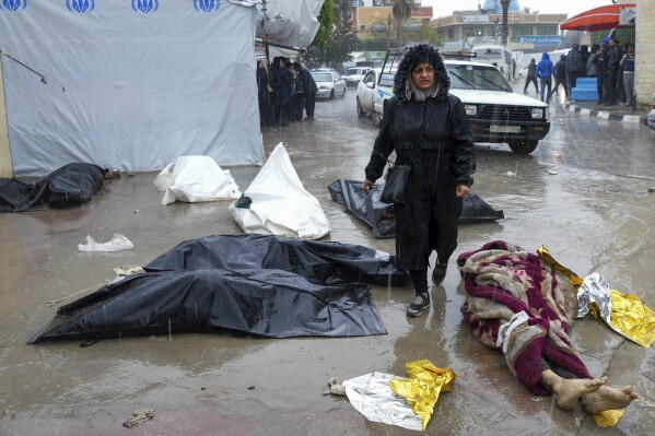 A woman walks among the bodies of Palestinians killed in Israeli bombing of the Gaza Strip in front of the Al-Aqsa hospital mortuary in Deir al-Balah, Gaza Strip, Sunday, February 18, 2024.  (AP Photo/Adel Hana)