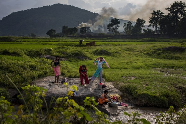 FILE - Smoke rises from a coal-powered steel plant in the background as village girls get ready after taking a bath in a stream at Hehal village near Ranchi, in eastern state of Jharkhand, Sept. 26, 2021. The final meeting of climate and environment ministers from the world's largest economies ended without an agreement or joint statement Friday, July 28, 2023, despite pleas from leading figures for nations to show a united front on climate change as weather records shatter across the globe. (AP Photo/Altaf Qadri, File)