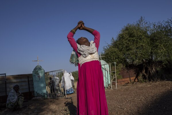 A Tigrayan woman who fled the conflict in Ethiopia's Tigray region stretches her arms after Sunday Mass ends at a nearby church, at Umm Rakouba refugee camp in Qadarif, eastern Sudan, Nov. 29, 2020. (AP Photo/Nariman El-Mofty)