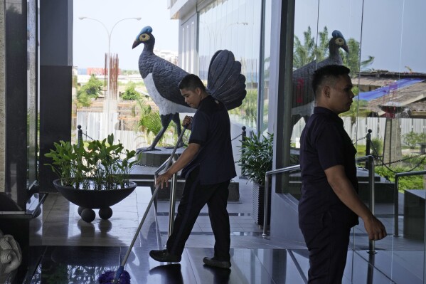 A worker mops the floor near the statue of a maleo at a hotel in Mamuju, West Sulawesi, Indonesia, Sunday, Oct. 29, 2023. The maleo is a critically endangered and declining species that's endemic to Sulawesi and its surrounding islands — a revered symbol of the country's lush biodiversity. But the bird now is facing a new threat as Indonesia builds a new capital hundreds of miles away. (AP Photo/Dita Alangkara)