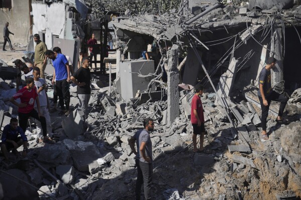 Palestinians look at buildings destroyed in the Israeli bombardment in the morgue in Deir al Balah, Gaza Strip, Tuesday, Nov. 7, 2023. (AP Photo/Hatem Moussa)