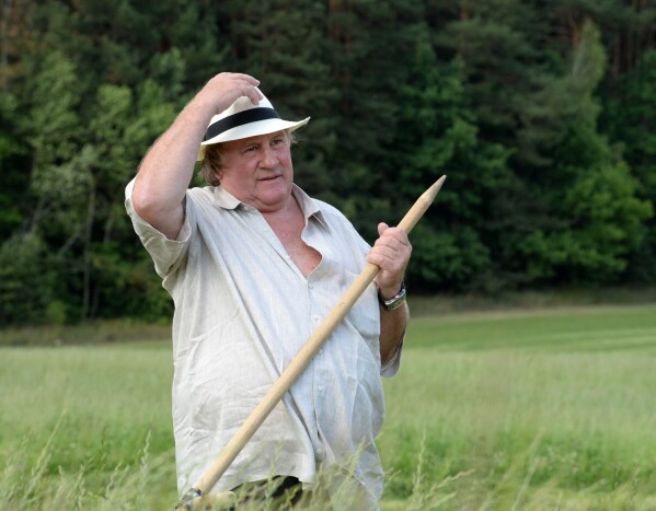 French actor Gerard Depardieu holds a hand scythe in the presidential residence of Ozerny, outside Minsk, Belarus, Wednesday, July 22, 2015. (Andrei Stasevich/BelTA Photo via AP)