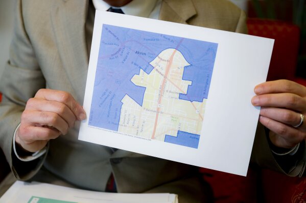 FILE - In this Thursday, April 11, 2019, file photo David Niven, a professor of political science at the University of Cincinnati, holds a map demonstrating a gerrymandered Ohio district in Cincinnati. The Supreme Court said, by a 5-4 vote on Thursday, June 27, 2019, that claims of partisan gerrymandering do not belong in federal court. The court's conservative, Republican-appointed majority says that voters and elected officials should be the arbiters of what is a political dispute The decision effectively reverses the outcome of rulings in Maryland, Michigan, North Carolina and Ohio, where courts had ordered new maps drawn. (AP Photo/John Minchillo, File)