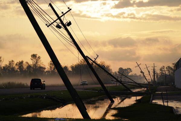 FILE - Downed power lines slump over a road in the aftermath of Hurricane Ida, Friday, Sept. 3, 2021, in Reserve, La. Weather disasters fueled by climate change now roll across the U.S. year-round, battering the nation's aging electric grid. (AP Photo/Matt Slocum, File)