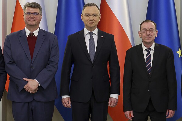 FILE -Poland's President Andrzej Duda, center, poses with former deputy interior minister Maciej Wasik, left, and former interior minister Mariusz Kaminski, right, in Warsaw, Poland, Tuesday, January, 9, 2004. Poland’s feud between the new pro-European Union government and conservative opposition has focused on parliament status of two opposition politicians just out of jail, after they were pardoned by their ally, president Andrzej Duda. Thursday’s session of the lower house of parliament opened amid questions whether two senior Law and Justice members. (AP Photo/President Palace/Jakub Szymczuk, File)